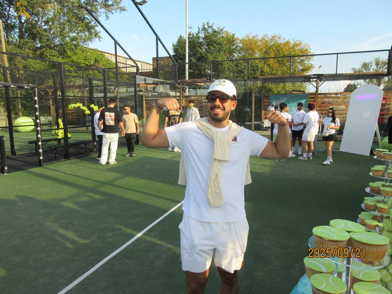 A member flexing mid-celebration beside the tennis-ball cupcake towers